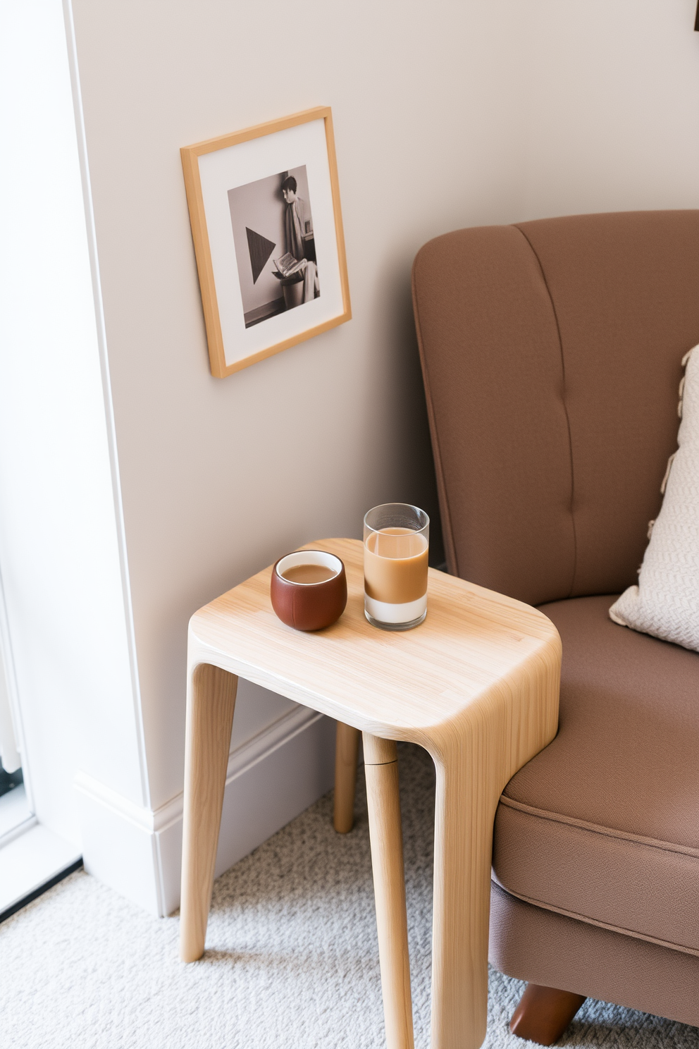 A cozy reading nook featuring a small side table designed for drinks and snacks. The table is made of light wood with a smooth finish, complemented by a plush armchair upholstered in soft fabric.