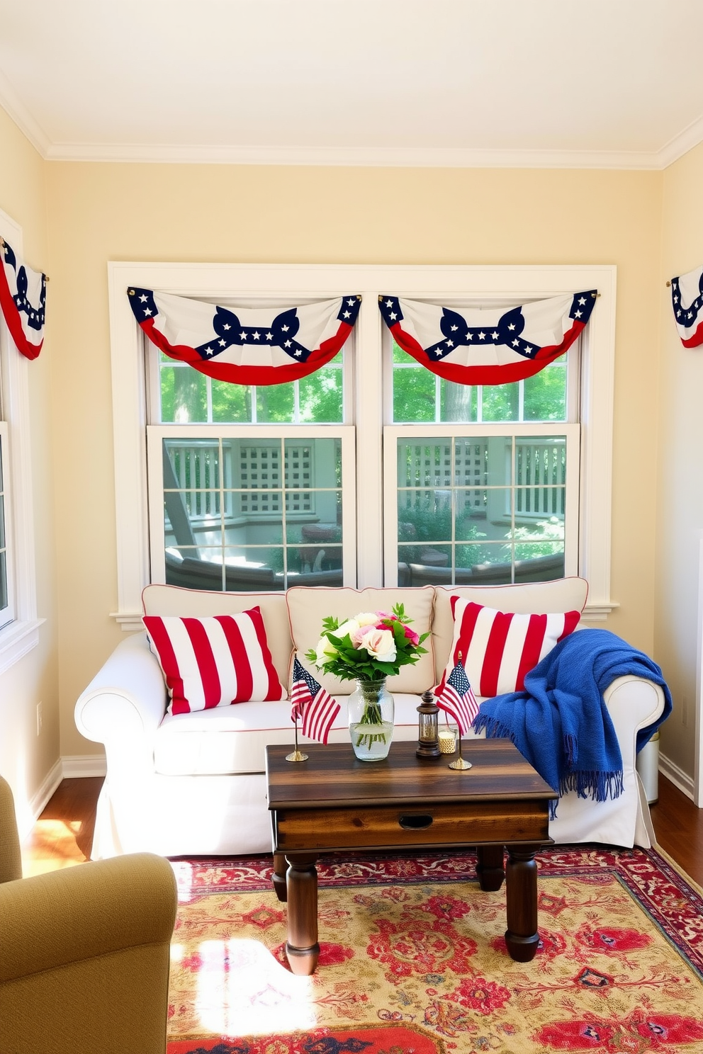 A cozy living room adorned with patriotic bunting draped elegantly across the windows. The space features a small sofa with red and white striped cushions, complemented by a blue throw blanket for a festive touch. A rustic coffee table sits in the center, decorated with a vase of fresh flowers and small American flags. The walls are painted in a soft cream color, and a colorful area rug anchors the seating arrangement, creating a warm and inviting atmosphere.