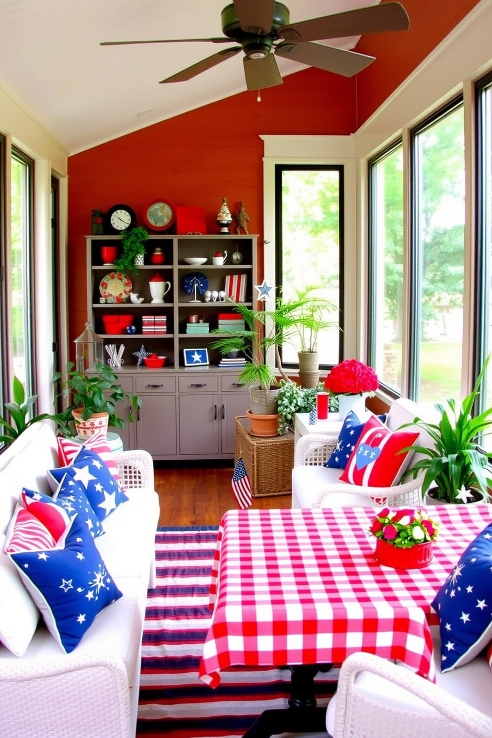 A sunroom decorated with patriotic red white and blue accents creates a festive and inviting atmosphere. The walls are adorned with vibrant red and blue throw pillows on a comfortable white sofa, complemented by a striped area rug that ties the colors together. Large windows allow natural light to flood the space, showcasing a collection of red white and blue decorative items on shelves. Potted plants in the corners add a touch of greenery, while a table set with a red and white checkered tablecloth invites gatherings with family and friends.