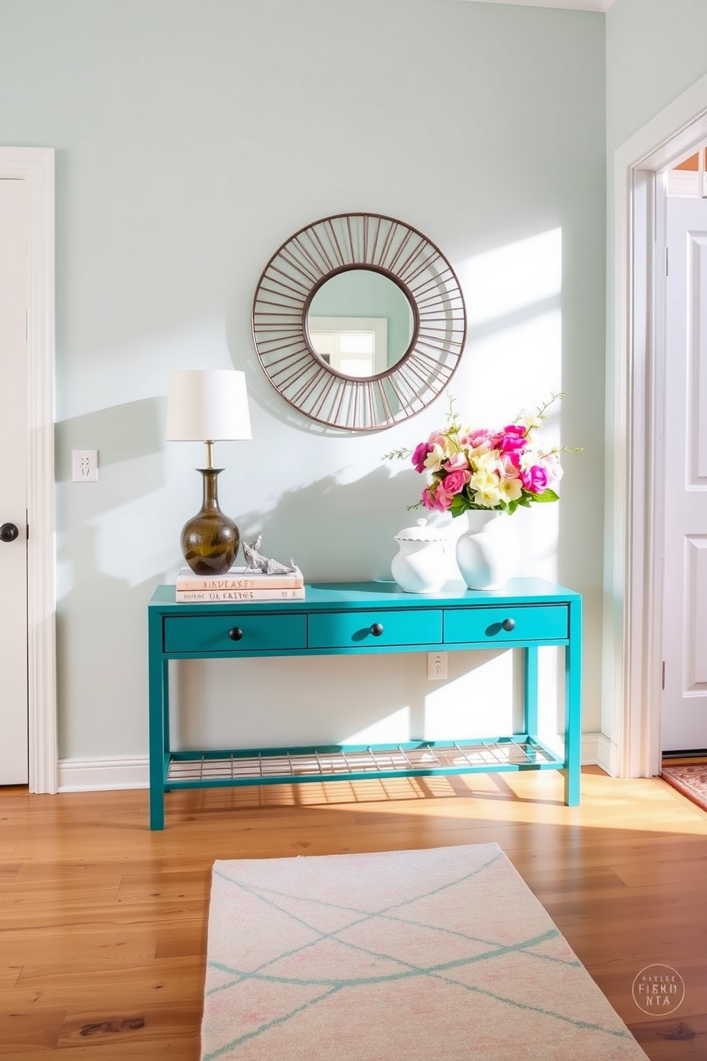 A vibrant entryway features a sleek console table painted in a bold teal color. Above the table, a large round mirror with a decorative frame reflects natural light, enhancing the space. The console is adorned with fresh spring flowers in a ceramic vase, adding a lively touch. A stylish runner rug in pastel hues leads guests into the home, creating a warm and inviting atmosphere.