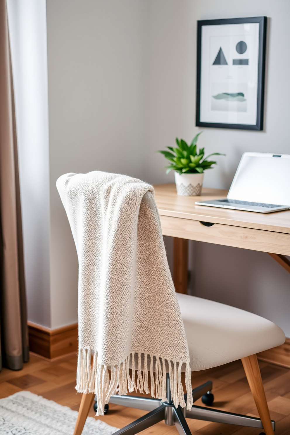 A cozy home office setting with a stylish chair adorned with a soft throw blanket draped over one arm. The desk is made of light wood, complemented by a potted plant and a sleek laptop, creating a refreshing spring atmosphere.