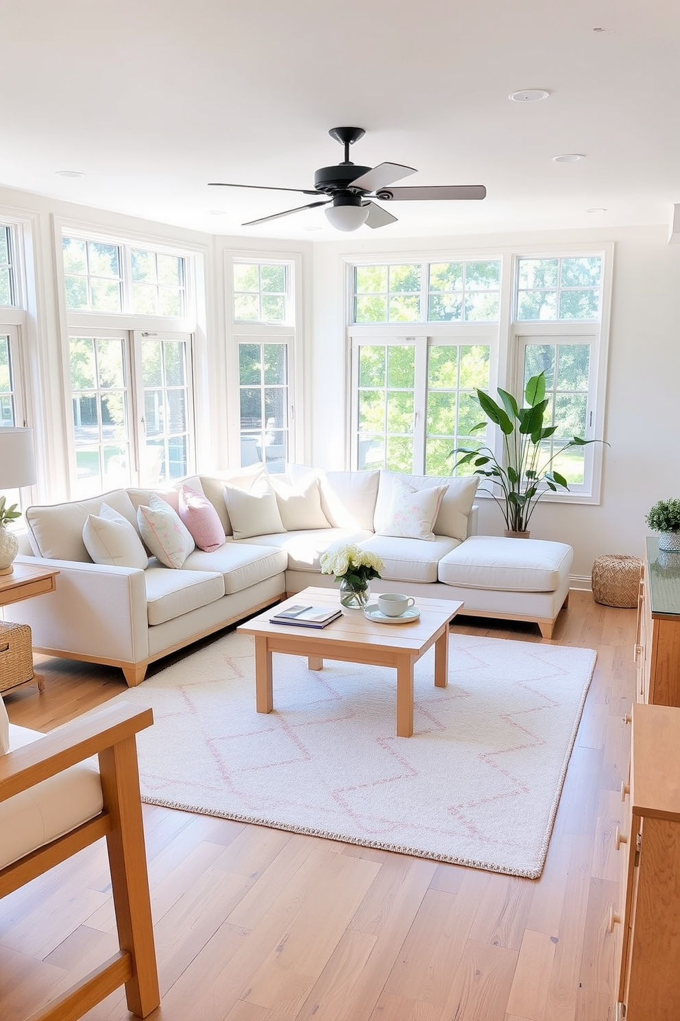 A bright and airy living room filled with natural light. The space features light wood accents in the furniture and decor, creating a warm and inviting atmosphere. A comfortable sectional sofa is adorned with pastel-colored throw pillows. A light wood coffee table sits at the center, complemented by a soft area rug with floral patterns.