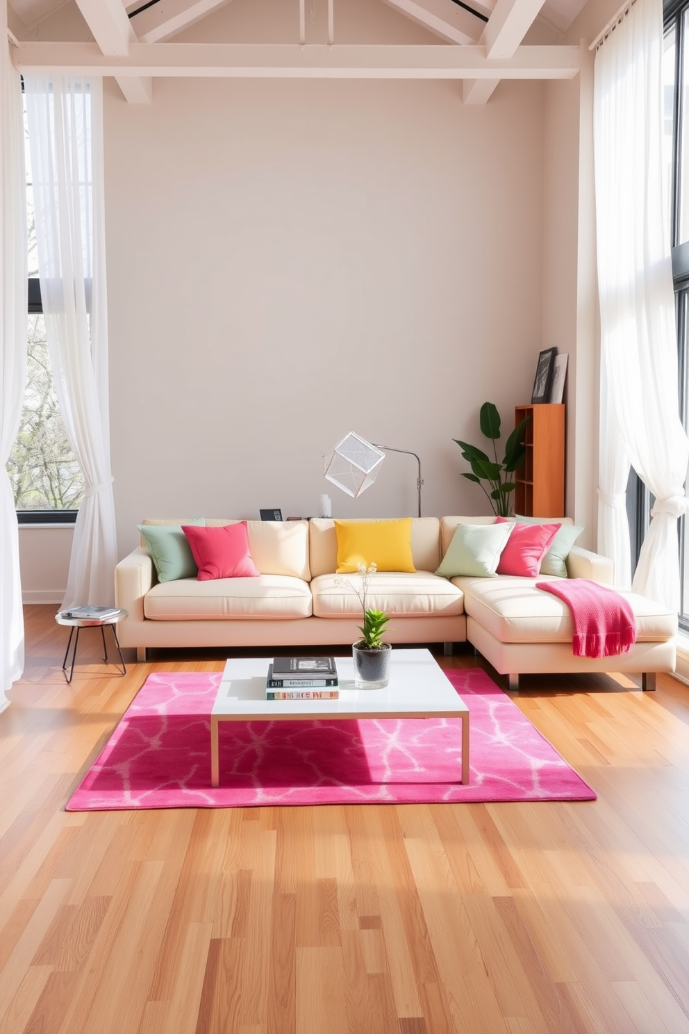 A bright and airy loft space filled with natural light. The room features a large sectional sofa in a soft pastel hue, complemented by vibrant throw pillows and a bright area rug that adds warmth to the hardwood floor. A modern coffee table sits at the center, adorned with a stack of art books and a small potted plant. Large windows draped with sheer white curtains offer a view of the blossoming spring landscape outside.