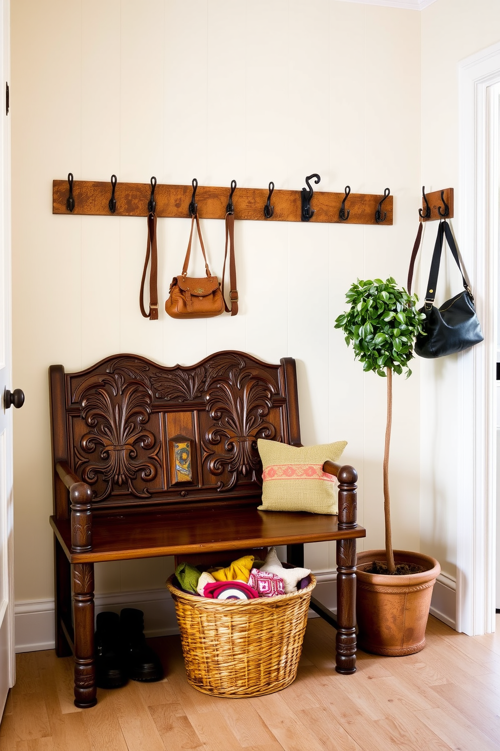 A charming mudroom features a vintage wooden bench with intricate carvings, providing a perfect spot to sit and remove shoes. Above the bench, a collection of antique hooks is mounted on the wall, ideal for hanging coats and bags. The walls are painted in a soft pastel color, creating a warm and inviting atmosphere. A woven basket sits on the floor, filled with colorful blankets and a potted plant adds a touch of greenery to the space.