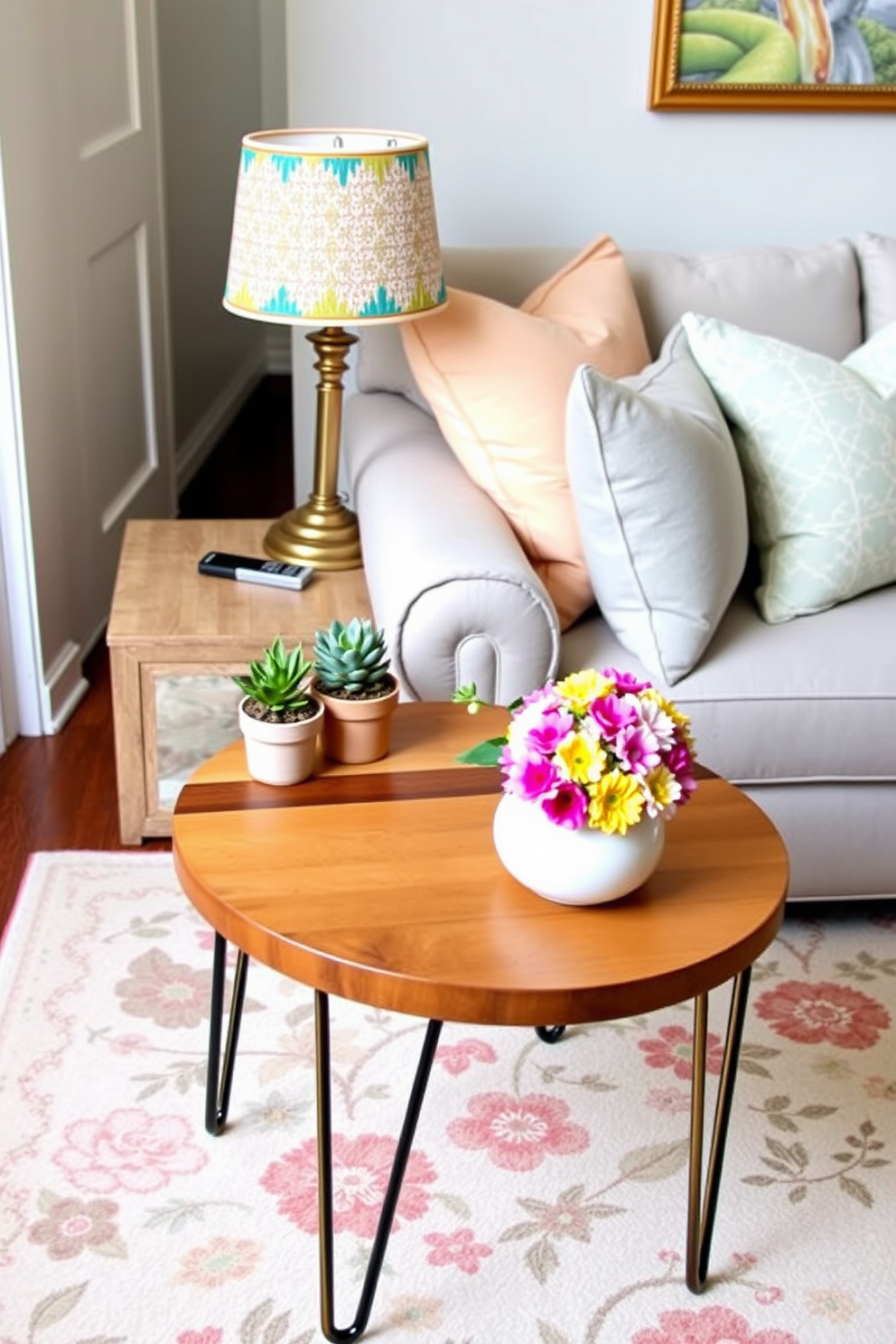 Charming side table with unique decor features a round top made of reclaimed wood and slender metal legs. Adorning the table is a small potted succulent alongside a vintage lamp with a colorful lampshade. Spring small living room decorating ideas include pastel-colored throw pillows on a light gray sofa and a soft area rug with floral patterns. A cheerful arrangement of fresh flowers in a ceramic vase sits on the coffee table, enhancing the vibrant atmosphere.