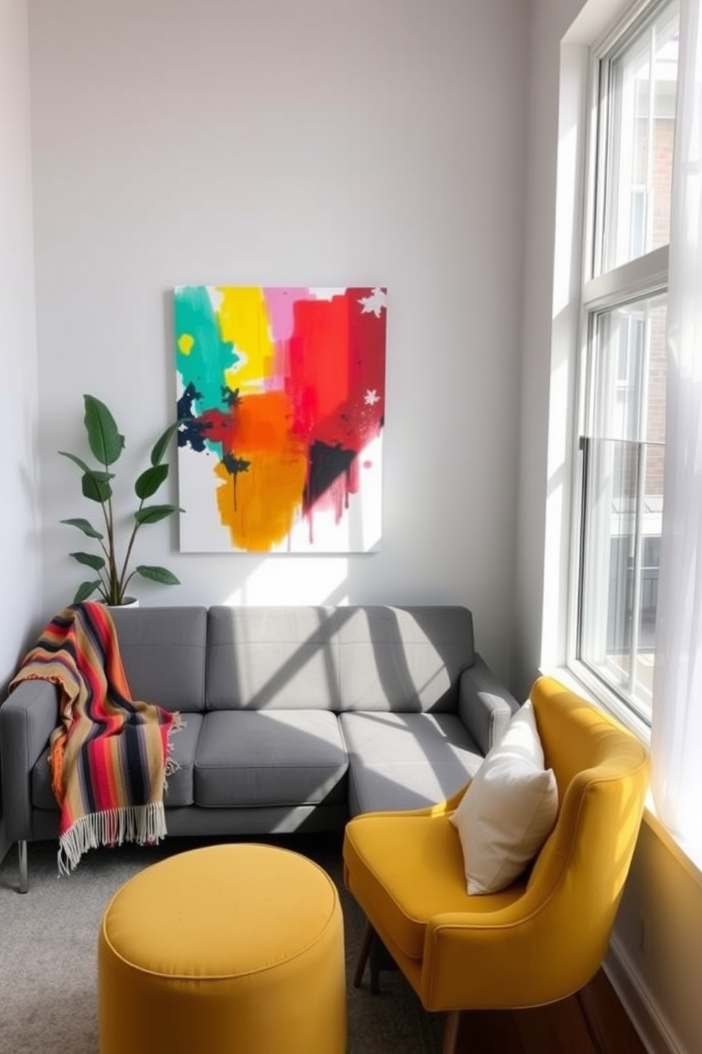 A vibrant small living area filled with natural light. The walls are painted in soft white, and a large abstract painting with bright colors hangs above a sleek gray sofa. In one corner, a small potted plant adds a touch of greenery. A colorful throw blanket drapes over the arm of the sofa, and a bright yellow accent chair complements the space beautifully.