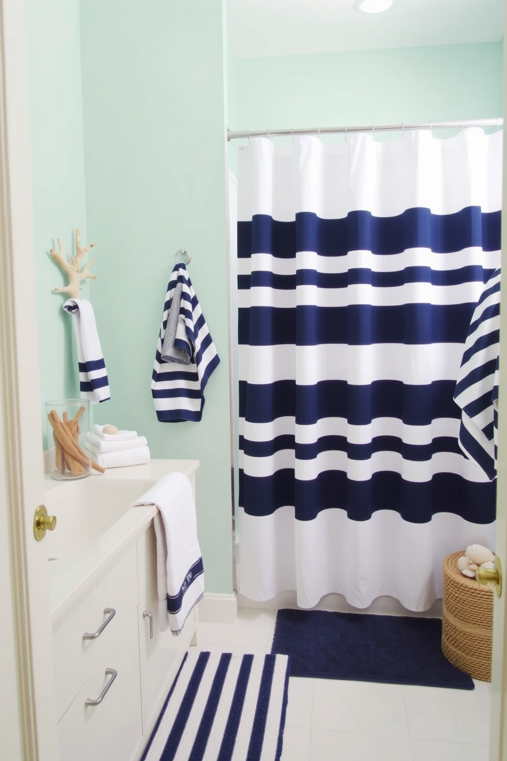 A bright and airy summer bathroom features nautical stripes in the textiles, creating a fresh coastal vibe. The shower curtain showcases bold navy and white stripes, complemented by matching towels and a striped bath mat. The walls are painted in a soft seafoam green, enhancing the nautical theme. Accents of driftwood decor and seashells add a charming touch to the overall design.