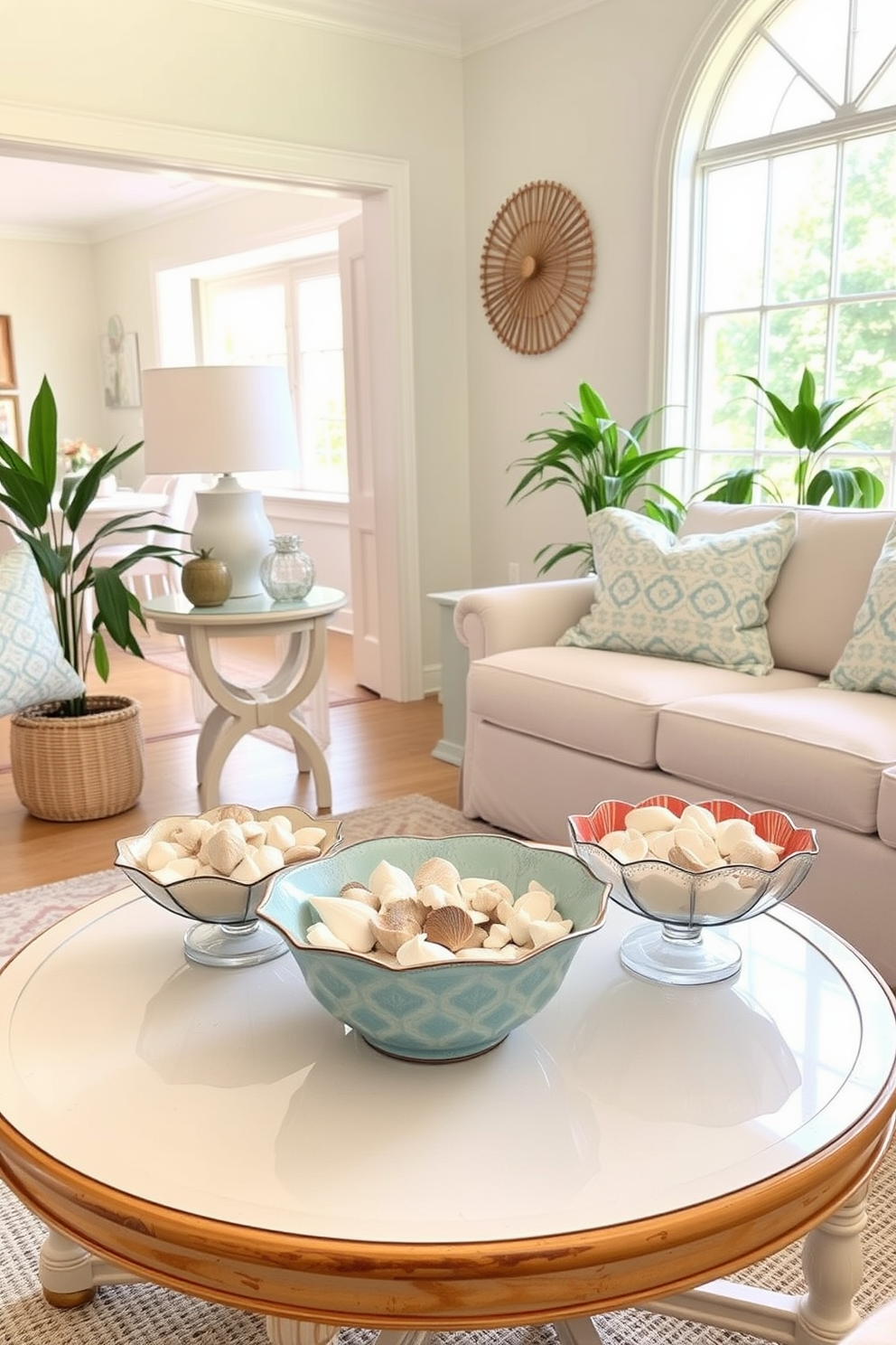 A bright and airy living room decorated for summer. A coffee table is adorned with decorative bowls filled with seashells, bringing a coastal vibe to the space. The walls are painted in soft pastel colors, enhancing the cheerful atmosphere. A large window allows natural light to flood in, illuminating the room and highlighting the seasonal decor.