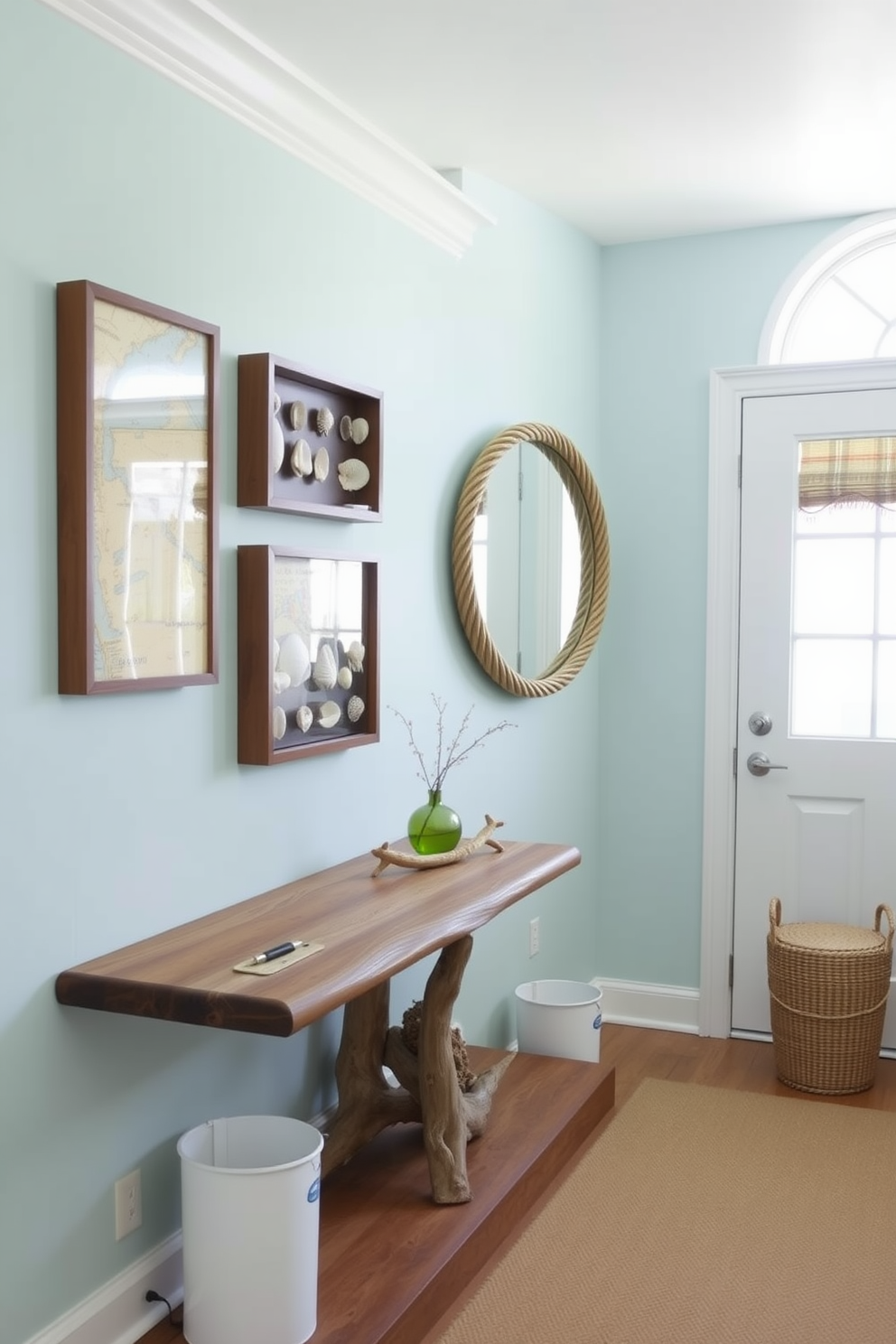 A bright and airy hallway decorated with nautical elements. The walls are painted in a soft seafoam blue, adorned with framed vintage maritime maps and a collection of seashells in shadow boxes. A wide wooden console table made from reclaimed driftwood sits against one wall. Above it, a large round mirror with a rope frame reflects the natural light streaming in through a nearby window.