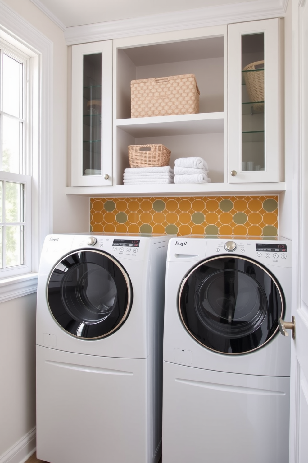 A bright and airy laundry room features a bold backsplash in a geometric pattern that adds a pop of color. The cabinetry is painted in a soft white, complementing the vibrant tiles and creating a fresh, inviting atmosphere. Natural light floods the space through a large window, highlighting the stylish open shelving adorned with neatly folded towels and decorative baskets. A sleek, modern washer and dryer sit side by side, providing both functionality and elegance in the design.