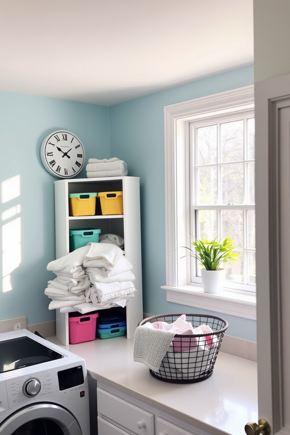 A cheerful laundry room filled with natural light. The walls are painted in a soft pastel blue, and a fun laundry-themed clock hangs prominently above a white shelving unit filled with colorful storage bins. A spacious countertop is cluttered with neatly folded towels and a basket of fresh laundry. A potted plant sits on the windowsill, adding a touch of greenery to the space.