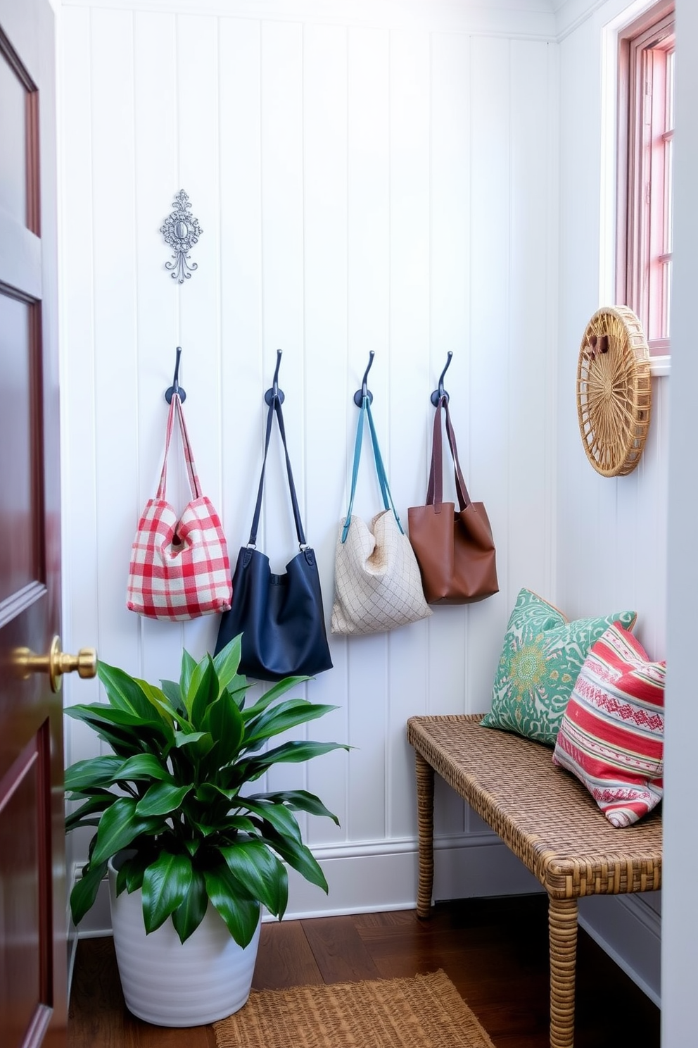 A bright and airy mudroom features a light-colored shiplap wall adorned with decorative hooks for bags. The space is enhanced by a woven bench with colorful cushions and a large potted plant in the corner, creating a welcoming atmosphere.