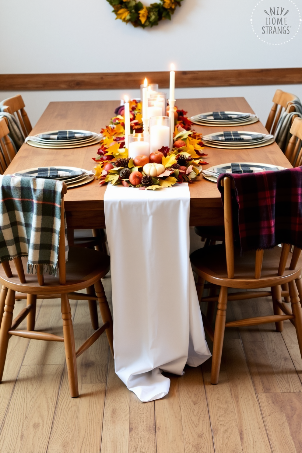 A rustic wooden table is adorned with a white linen tablecloth that drapes elegantly to the floor. Centered on the table is a vibrant arrangement of autumn leaves, pinecones, and small pumpkins, creating a warm and inviting atmosphere for Thanksgiving. Surrounding the table are mismatched wooden chairs, each with a cozy plaid throw draped over the back. Flickering candles in varying heights are placed along the center, casting a soft glow and enhancing the rustic charm of the setting.