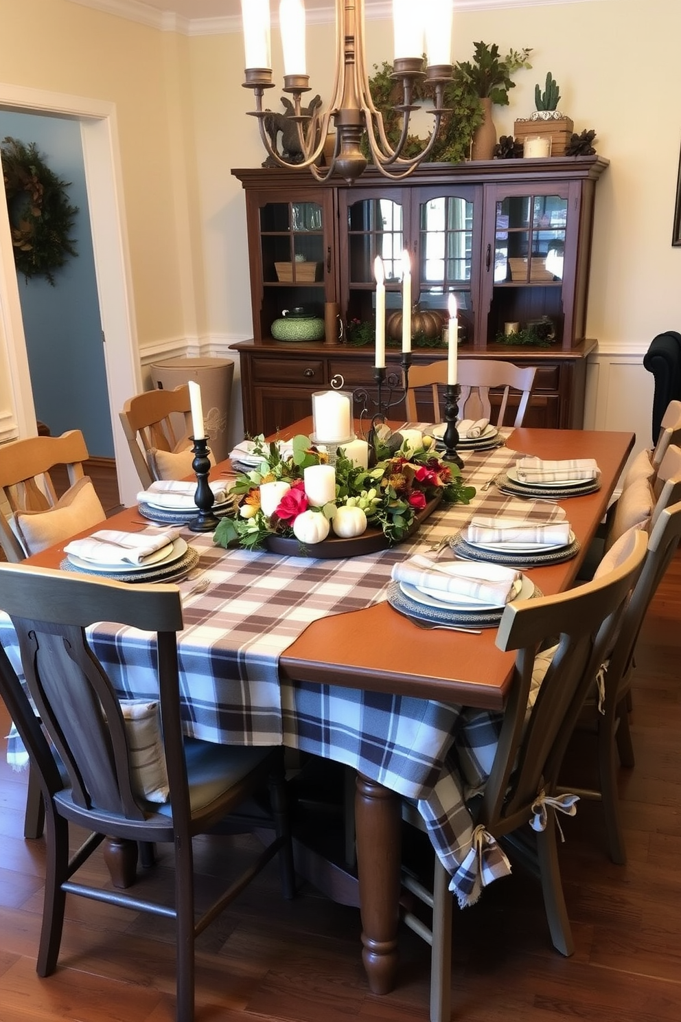 A warm and inviting dining room is set for Thanksgiving with a large wooden table covered in a classic plaid tablecloth. Surrounding the table are mismatched chairs, each adorned with soft cushions that add comfort and charm to the space. The centerpiece features a rustic arrangement of seasonal flowers and greenery, complemented by flickering candles in elegant holders. The walls are painted in a warm cream color, and autumn-themed decorations are scattered throughout the room, enhancing the cozy atmosphere.