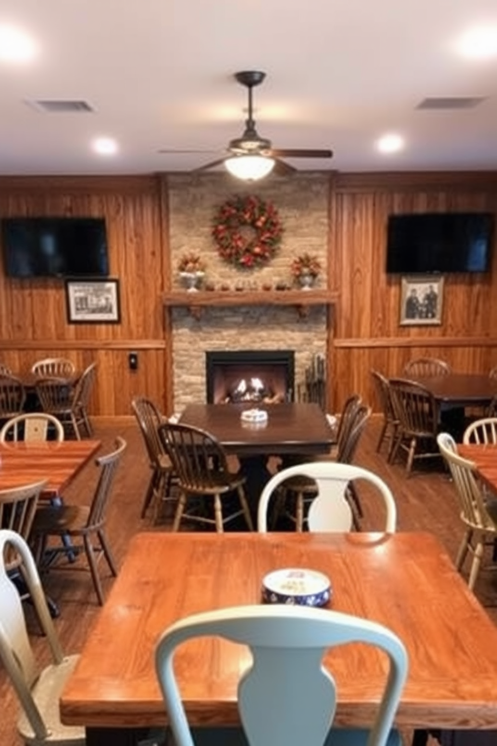 A cozy game room designed for family fun during Thanksgiving features rustic wooden game tables surrounded by mismatched chairs. The walls are adorned with warm-toned wood paneling, and a large fireplace serves as the room's focal point, creating a welcoming atmosphere.