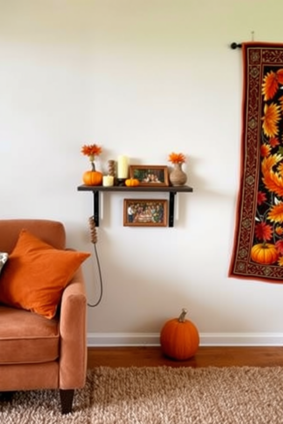 A cozy living room featuring a small wall-mounted shelf adorned with autumn-themed decorations. On the shelf, there are small pumpkins, candles, and a framed picture of a Thanksgiving gathering. Adjacent to the shelf, a vibrant tapestry depicting fall leaves hangs on the wall. The floor is covered with a warm, textured rug that adds comfort to the limited space.