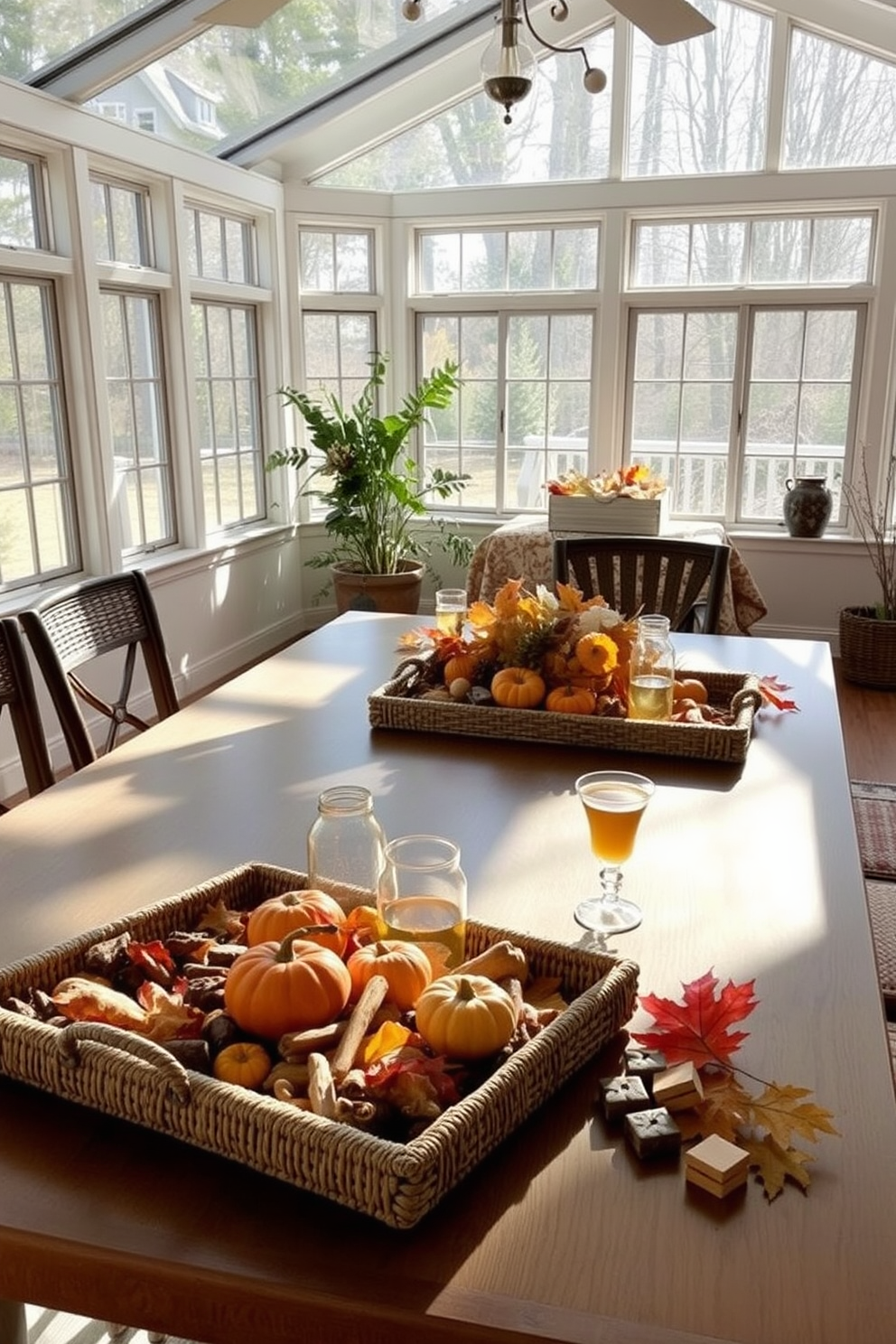 A cozy sunroom filled with natural light features a large table adorned with decorative trays holding an assortment of snacks and drinks for Thanksgiving. The trays are made of woven materials and are complemented by seasonal decorations like small pumpkins and autumn leaves.