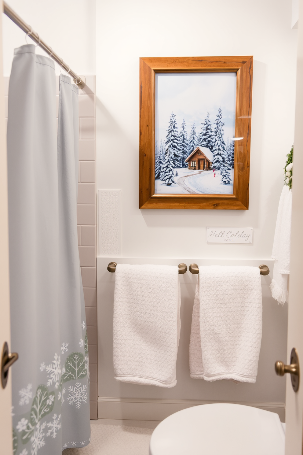 Holiday themed artwork for wall decor. The artwork features a serene winter landscape with snow-covered trees and a cozy cabin, beautifully framed in rustic wood. The bathroom is adorned with soft white and pale blue accents, creating a tranquil atmosphere. Plush towels and a festive shower curtain complement the winter theme, inviting warmth and comfort.