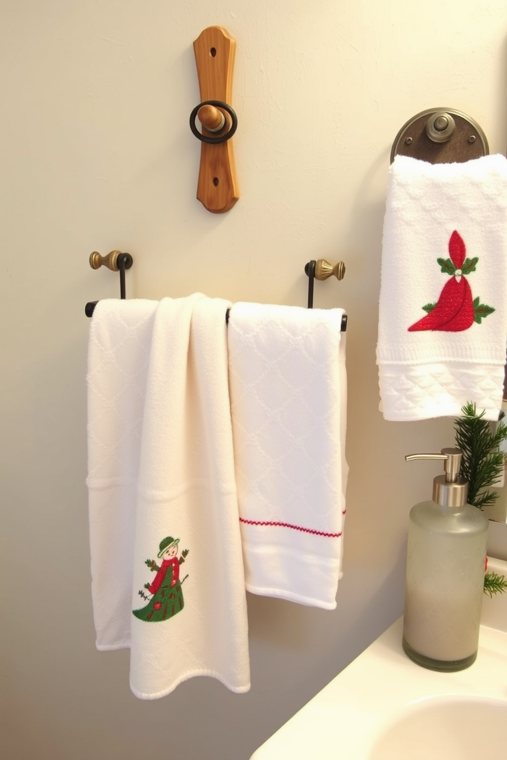 Create a cozy winter bathroom setting adorned with decorative towels featuring festive holiday motifs. The towels are neatly arranged on a wooden towel rack, complemented by a frosted glass soap dispenser and a small evergreen arrangement on the vanity.