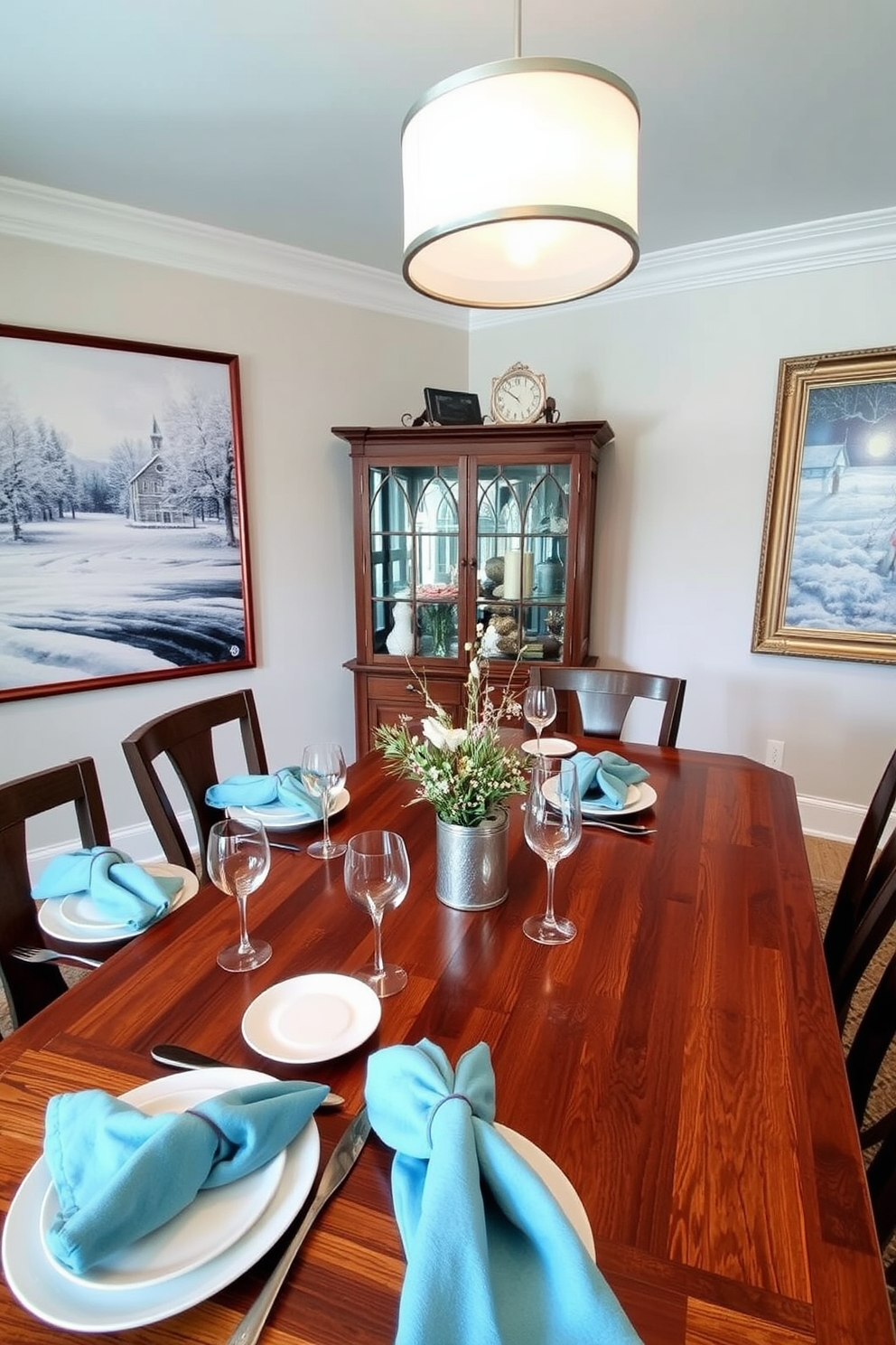 Seasonal artwork featuring snow-covered landscapes and cozy winter scenes adorns the walls of the dining room. A large wooden table is set with elegant white dinnerware and soft blue napkins, creating a warm and inviting atmosphere for winter gatherings.