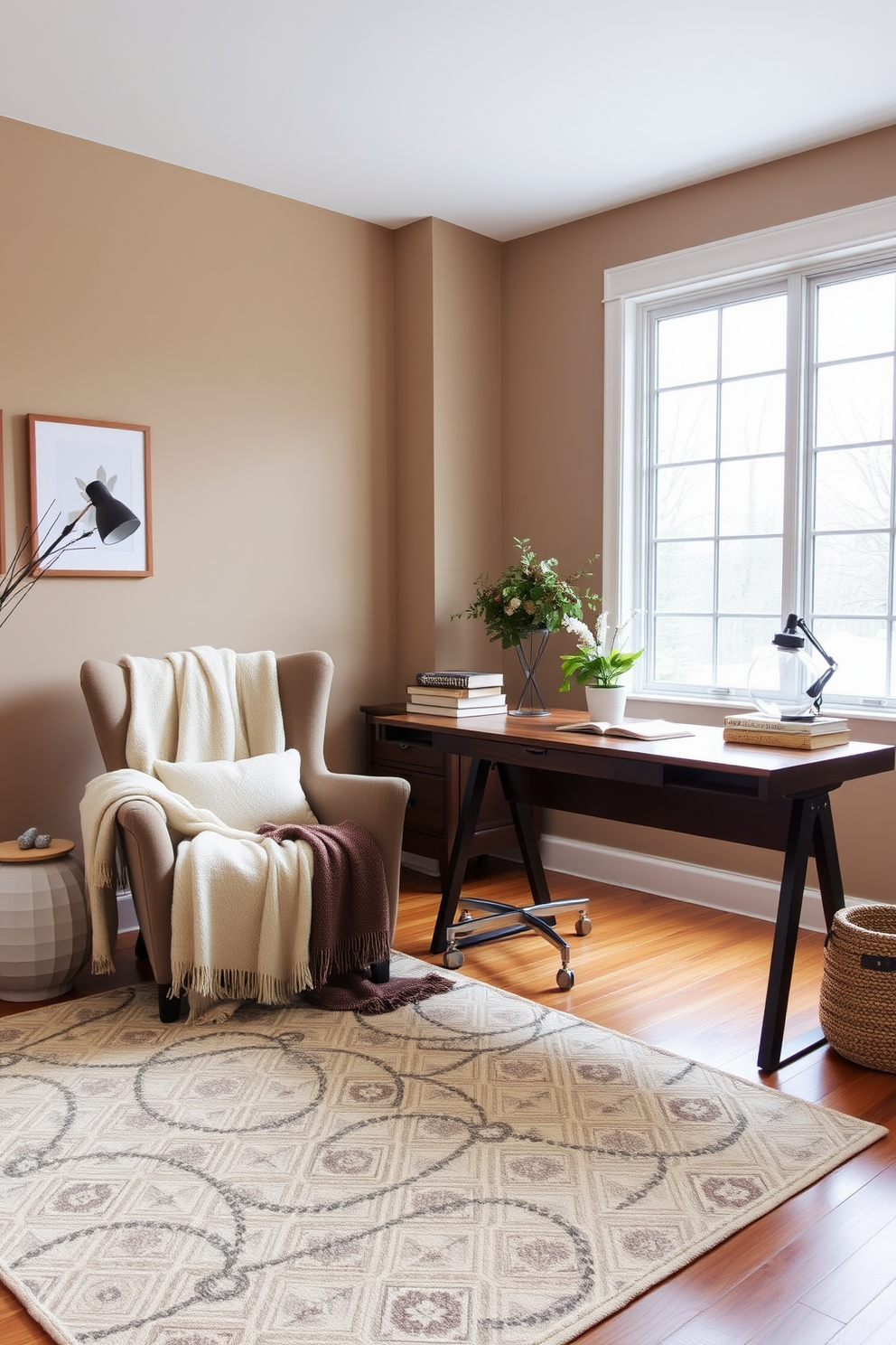 A cozy winter home office setting. Soft blankets are draped over a plush armchair and a sleek wooden desk, creating an inviting atmosphere. The walls are painted in a warm taupe color, and a large window allows natural light to fill the space. A stylish area rug adds texture to the hardwood floor, complementing the overall design.