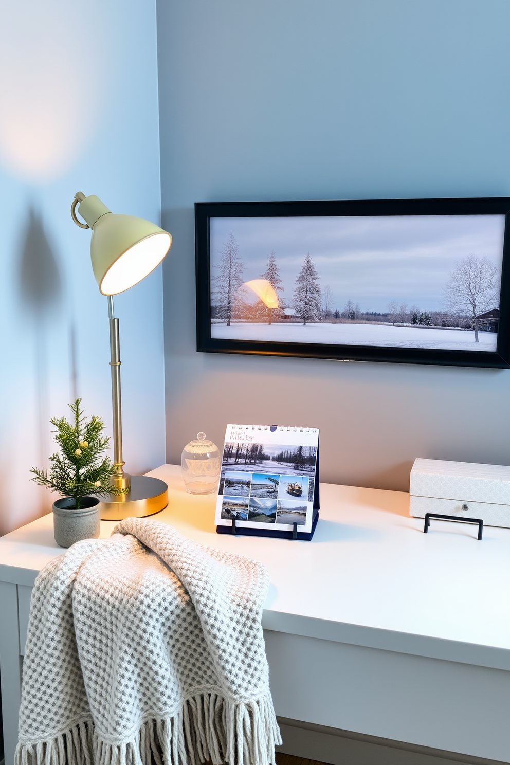 A stylish home office featuring a desk calendar showcasing serene winter scenes. The desk is adorned with a cozy throw blanket and a warm-toned lamp, creating an inviting workspace. The walls are painted in a soft blue hue, reminiscent of a winter sky. A small potted evergreen sits on the desk, adding a touch of nature to the winter-themed decor.