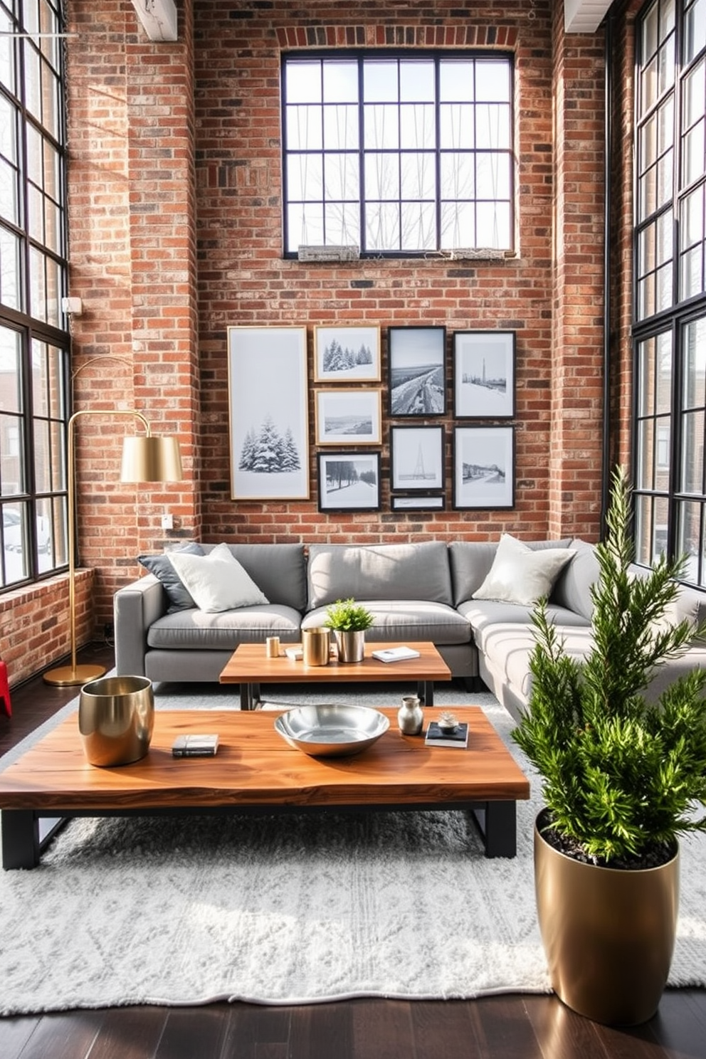 A cozy winter loft space featuring exposed brick walls and large windows that allow natural light to flood in. The room is adorned with a plush gray sectional sofa and a rustic wooden coffee table, complemented by metallic accents like a gold floor lamp and silver decorative trays. A large area rug in soft whites and grays anchors the seating area, while a gallery wall of framed winter landscapes adds a personal touch. Potted evergreen plants in sleek metallic planters bring a refreshing pop of color and life to the space.