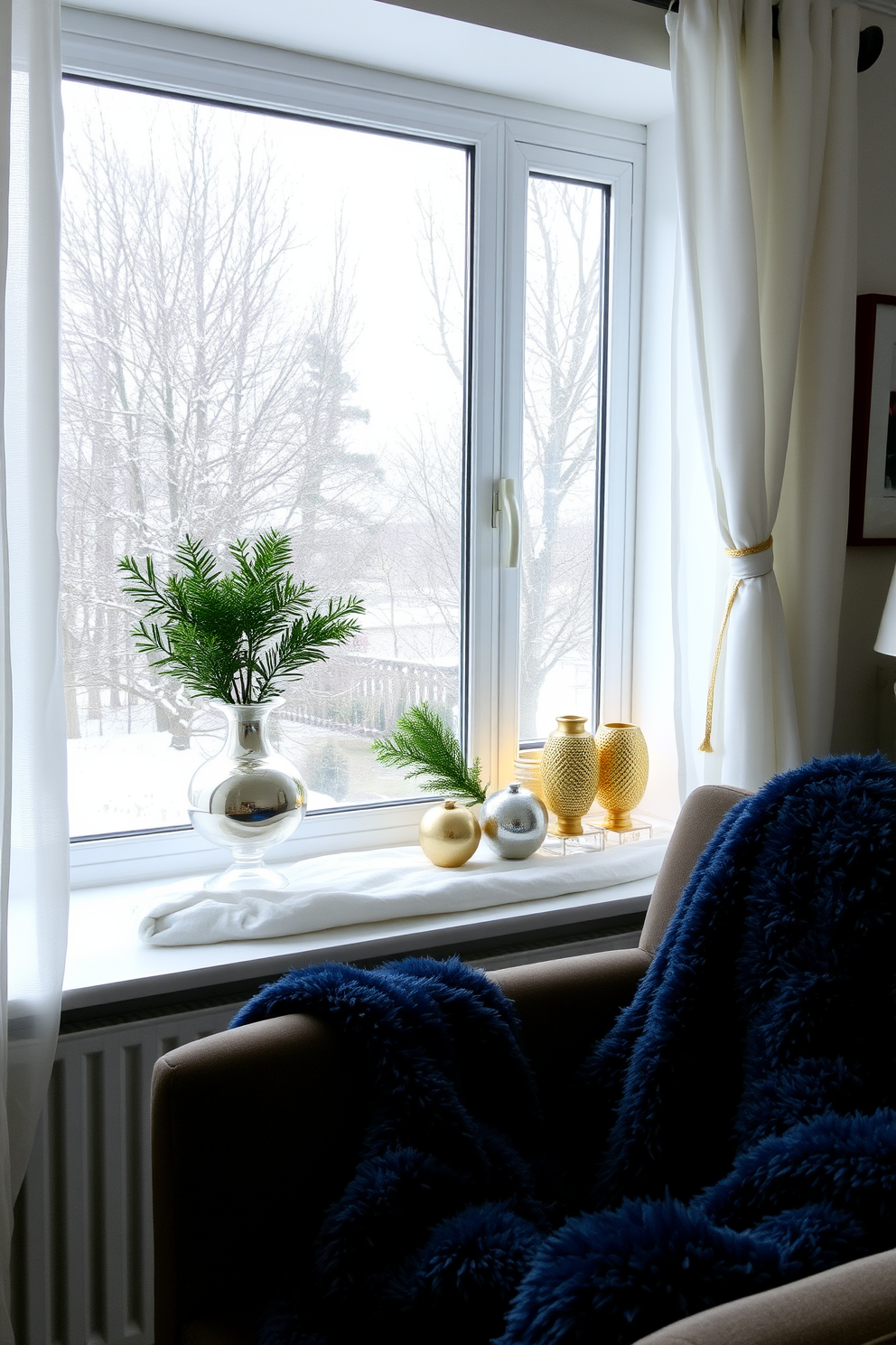 A cozy winter living room setting. There's a large window adorned with sheer white curtains and gold tiebacks, allowing soft natural light to filter in. On the windowsill, a collection of metallic gold and silver decorative items sits alongside evergreen branches in a vase. A plush throw blanket in deep blue is draped over a stylish armchair, adding warmth and contrast to the space.